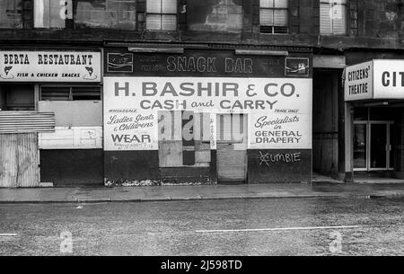 Schwarz-Weiß-Archivbild des geschlossenen H Bashir & Co Cash and Carry Shop-Geländes mit Cumbie Gang-Schild in der Gorbals Street, Glasgow. Cumbie waren eine der berüchtigten Banden der Gorbals-Gegend von Glasgow. Foto aufgenommen im März 1977. Austausch von TAF2AT. Stockfoto