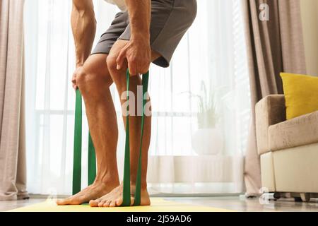 Junger und muskulöser Mann beim Heimtraining mit einem Widerstand Gummibänder Stockfoto