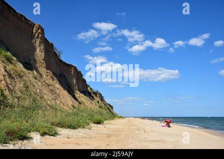 Schaumende Meereswellen Rollen am Sandstrand am Tag. Urlauber können in der Ferne Sonnenbaden und schwimmen Stockfoto