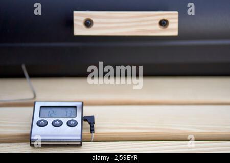 Kerntemperatursensor (Kerntemperatursensor). Digitales Messgerät mit Display auf Holzplatte vom Grill für den Grill. Stockfoto