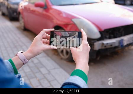 Weibliche Hände, die Fotos von Autoschäden in Nahaufnahme des Mobiltelefons machen Stockfoto