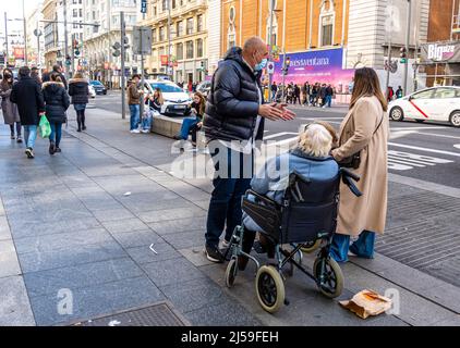 Mann und Frau, die sich auf einem Rollstuhl in der Straße von madrid, Spanien, um eine alte Dame kümmern. Behinderte Frauen in Rollstuhl im Freien. Stockfoto