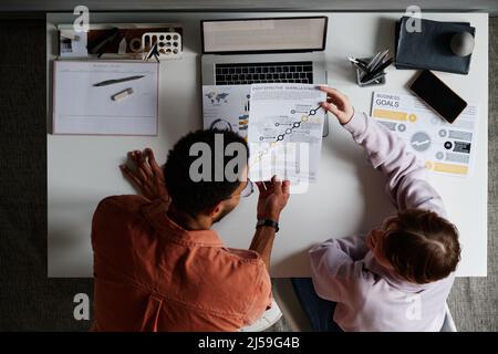 Aus der Perspektive junger multiethnischer Kollegen, die ihre Papiere analysieren und ihre Strategie im Büro diskutieren Stockfoto