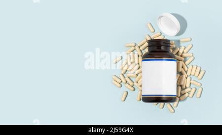 Natürliche Farbkapseln und Glasflasche auf hellblauem Hintergrund. Vitamine, biologisch aktive Zusatzstoffe Zusammensetzung. Gesundes Immunitätskonzept Stockfoto