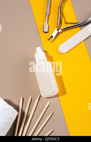 Eine Reihe von Maniküre-Tools, klebt auf einem Hintergrund von Orange und Kaffee Farben. Eine Flasche Kutikula-Gel auf einem orangefarbenen Hintergrund. Nagelpflege, Design Stockfoto