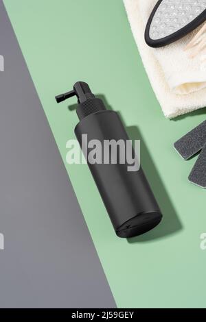 Ein Set von Pediküre-Werkzeugen und eine Flasche Kosmetik auf einem Hintergrund von grünen und grauen Farben. Eine Flasche Pediküre. Fußhautpflege, WELLNESS-Kosmetik Stockfoto