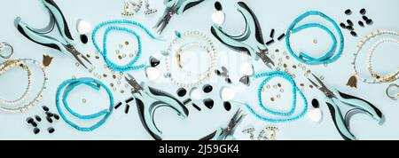 Werkzeuge und Zubehör für DIY-Schmuck am Arbeitsplatz. Flach lag auf blauem cyanfarbenem Hintergrund. Kreative, flache Lay-Gestaltung, Panorama-Komposition, extra breites Banner Stockfoto