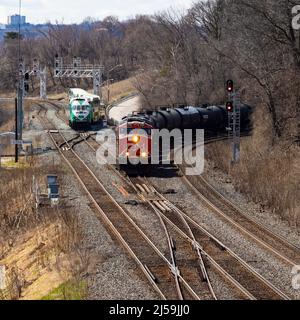 Güterzug und Pendler-Personenzug auf Eisenbahngleisen. Hamilton, Ontario, Kanada Stockfoto