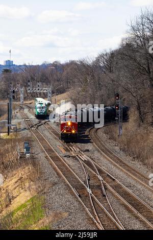 Güterzug und Pendler-Personenzug auf Eisenbahngleisen. Hamilton, Ontario, Kanada Stockfoto