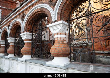 Schöner Zaun aus rotem Ziegelstein und durchbrochenen geschmiedeten Gittern. Fragment der Architektur der Kirche der Darstellung des Herrn in Jaroslaw Stockfoto