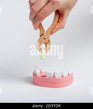 Zahnarzt Hand ziehen kranken Zahn mit Zange aus Kiefermodell. Zahnextraktion. Zahnprobleme, Parodontitis, Karies, Trauma-Konzept. Kinderspielzeug. Hochwertige Fotos Stockfoto