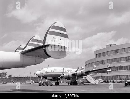 1950S SIGNATURE TRIPLE FIN TAIL VON FLUGZEUGEN DER TWA-KONSTELLATION 4-MOTORIGE PROPELLERFLUGZEUGE AUF ASPHALT AM FLUGHAFEN - A89 CRS001 HARS WEITWINKEL PROPELLER ABENTEUER FLUGZEUGE KUNDENSERVICE AUSSEN NIEDRIGEN WINKEL LEISTUNGSSTARKE FORTSCHRITT FIN INNOVATION STOLZ ASPHALT LUFTFAHRT BERUFE STAIRWAY TRIPLE 1943 KONZEPTIONELLE KONSTELLATION UNTERSCHRIFT STILVOLLE TWA LOCKHEED TRANS WORLD AIRLINES AIRLINER SCHWARZ-WEISS ZIVILIST IKONISCHEN ALTMODISCH ELEGANT Stockfoto