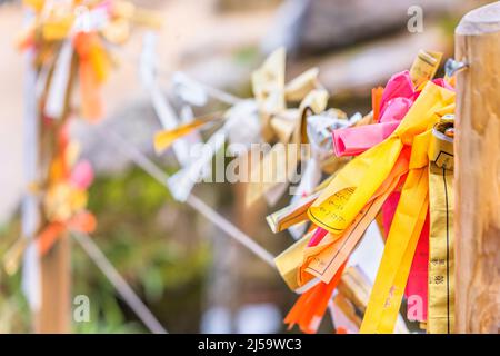 tokio, japan - 07 2021. dezember: Nahaufnahme von bunten shintoist-O-mikuji-Wahrsagerpapieren, die an den Seilen eines hölzernen Omikujikake im Dazai gefaltet sind Stockfoto