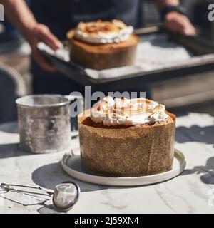 Traditioneller russischer und ukrainischer kulich kulich gefüllt mit Kondensmilch, frisch gebacken. Konditor im Hintergrund. Stockfoto