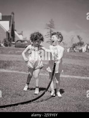 1940S LACHENDE JUNGE UND MÄDCHEN SPIELEN IM HOF SPRITZWASSER AUS GARTENSCHLAUCH SOMMERSPASS - J167 HAR001 HARS JUVENILE YARD-STIL KOMMUNIKATION COOL FREUND SCHLAUCH FREUDE LIFESTYLE FRAUEN HÄUSER BRÜDER GESUNDHEIT ZU HAUSE LEBEN KOPIEREN RAUM FREUNDSCHAFT VOLLE LÄNGE PERSONEN WOHN MÄNNER GEBÄUDE GESCHWISTER SCHWESTERN B&W SOMMER NACHBARN GLÜCK NACHBARSCHAFT ABENTEUER UND AUFREGUNG ERHOLUNG HÄUSER GESCHWISTER VERBINDUNG FREUNDLICHE RESIDENZ PLANSCHEN PANORAMA KOOPERATION VORGARTEN WACHSTUM ERFRISCHENDE SAISON ZWEISAMKEIT SCHWARZ UND WEISS KAUKASISCHEN ETHNIZITÄT HAR001 ALTMODISCHE SPIELKAMERADEN Stockfoto