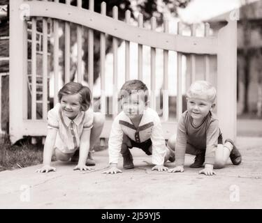 1930S 3 KINDER, ZWEI JUNGEN UND EIN MÄDCHEN IN EINER SCHLANGE, ALS OB SIE EINE STRECKE UND EIN FELD BEGINNEN WÜRDEN RENNEN WARTEN AUF DAS SIGNAL, UM DURCH TOR LAUFEN - J428 HAR001 HARS WETTBEWERB ERFREUT FREUDE LIFESTYLE FRAUEN BEREIT BRÜDER GESUNDHEIT HEIM LEBEN KOPIEREN RAUM FREUNDSCHAFT HALBE LÄNGE MÄNNER GESCHWISTER VERTRAUEN SCHWESTERN BEGINNEN ZU KRIECHEN B&W TOR KNIEN AKTIVITÄT GLÜCK FRÖHLICHES ABENTEUER UND AUFREGUNG LOW ANGLE ERWARTUNG GESCHWISTER LÄCHELT FREUNDLICH FREUDIGE ZUSAMMENARBEIT WACHSTUM JUGENDLICHE ZWEISAMKEIT SCHWARZ UND WEISS KAUKASISCHE ETHNIE HAR001 KNIEN ALTMODISCH Stockfoto