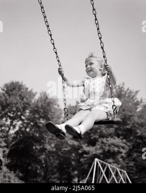 1950S AUFGEREGT LÄCHELNDES KLEINES MÄDCHEN, DAS AUF EINEM SPIELPLATZ HOCH FLIEGT - J7588 HAR001 HARS LIFESTYLE ZUFRIEDENHEIT FRAUEN GESUNDHEIT HOME LEBEN KOPIEREN RAUM VOLLER LÄNGE VERTRAUEN AUSDRÜCKE B&W SOMMERZEIT FREIHEIT TRÄUME HUMORVOLLES GLÜCK FRÖHLICH ABENTEUER FREIZEIT AUFREGUNG LOW ANGLE KOMISCH REGIE MARY JANE LÄCHELT SCHWINGENDE KOMÖDIE FREUDIGES WACHSTUM HOCHFLIEGENDE JUGENDLICHE ENTSPANNUNG SAISON SCHWARZ-WEISS KAUKASISCHE ETHNIE HAR001 ALT MODISCH Stockfoto