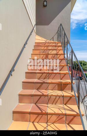 Geflieste Außentreppe eines Hauses mit schmiedeeisernem Geländer in San Francisco, Kalifornien. Treppeneingang eines Hauses mit Blick auf den Parkplatz l Stockfoto