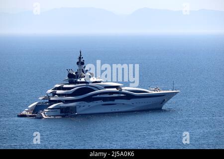 Luxusyacht mit Hubschrauberlandeplatz und Hubschraubersegeln im Meer, Seitenansicht. Weißes futuristisches Boot auf Berg Insel Hintergrund Stockfoto