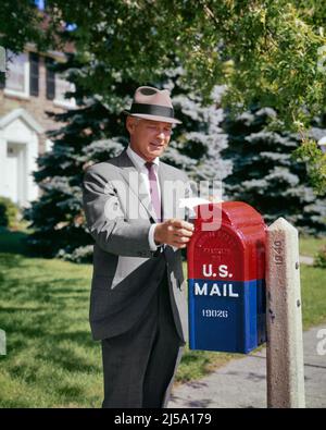 1960S GESCHÄFTSMANN, DER POST IN EINE ALTMODISCHE, GUSSEISERNE US-BRIEFKISTE AN DER STRASSENECKE IN EINEM VORORT EINLEGT - KP1229 HAR001 HARS NORTH AMERICAN ANZUG UND BINDEN AN AUF GEMALTEN MAILING BEQUEME US-MAIL USPS MID-ADULT MANN MID-ADULT FRAU VEREINIGTE STAATEN POSTDIENST GUSSEISEN KAUKASISCHE ETHNIZITÄT HAR001 ALTMODISCH Stockfoto