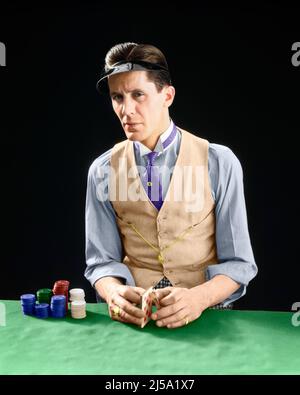 SPIELER-DEALER MIT 1910S 1920S FIGUREN, DER EIN VISOR-SHUFFLING-DECK MIT POKERCHIPS-KARTENHAI TRÄGT UND DIE KAMERA ANSCHAUT - S5222C HAR001 HARS RISIKO VERTRAUEN DEALER WESTE MITTLEREN ALTERS MANN BLICKKONTAKT GLÜCKSSPIEL POKER SCHATTET SEINEN CHEAT CRAVAT CON MANN CROOK SCHURKEN SHYSTER ÜBERPRÜFT STERN BERUFE SCHARFE SCHWINDLER QUOTEN HAI WETTEN STILVOLLE SHUFFLING MITTLEREN ERWACHSENEN MITTLEREN ERWACHSENEN MANN NICHT VERTRAUENSWÜRDIG VISIER KAUKASISCHEN ETHNIE SPIELER GRINSEND HAR001 ALTMODISCH VERDÄCHTIG Stockfoto