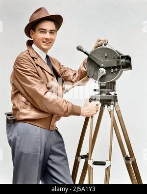 1930S LÄCHELNDER MANN KAMERAMANN BEDIENUNG AKELEY HANDKURBEL FILMKAMERA BLICK AUF KAMERA IN LEDERJACKE FEDORA HUT - U153C HAR001 HARS KOMMUNIKATION KARRIERE TECHNOLOGIE INFORMATION FREUDE LIFESTYLE JOBS STUDIO SCHUSS BEWEGUNG FILMEN KOPIEREN RAUM HALBE LÄNGE PERSONEN INSPIRATION MÄNNER KAMERAMANN BERUF VERTRAUEN TRAGBARES STATIV AUGENKONTAKT KURBEL FEDORA GESCHICKLICHKEIT BERUF GLÜCK FÄHIGKEITEN BETRIEB FRÖHLICH ABENTEUER STRATEGIE KARRIERE WAHL WISSEN RICHTUNG ARBEIT STOLZ AUF AUTORITÄT BESCHÄFTIGUNG BERUFE LÄCHELT VERBINDUNG KONZEPTIONELLE PHANTASIE FREUDIG STILVOLLE MITARBEITER Stockfoto