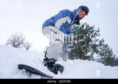 Snowboarder steht auf den Pisten des Berges mit einem Snowboard in Skiausrüstung Stockfoto