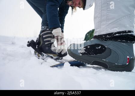 Fuß im Stiefel hält ein Snowboard auf einer Piste Stockfoto