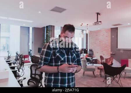 Office Manager arbeiten im Coworking Space mit einem Smartphone, das Online-Markttrends analysiert, fokussierte Mitarbeiter beim Lesen von Finanznachrichten oder beim Surfen Stockfoto