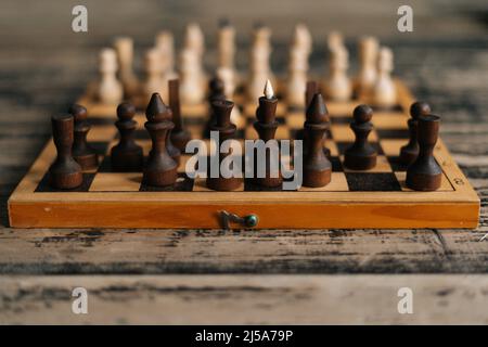 Nahaufnahme des Schachbretts auf einem hölzernen Vintage-Tisch im dunklen Raum, selektiver Fokus, Nahaufnahme. Stockfoto