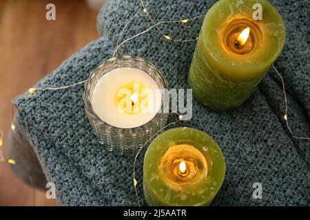 Brennende Kerzen und leuchtende Lichter auf dem Tisch, Nahaufnahme Stockfoto