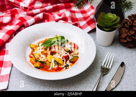 Ein tiefer Teller Zucchini-Gemüseeintopf mit geriebenem Käse und Basilikumblättern. Hausgemachte Speisen. Stockfoto