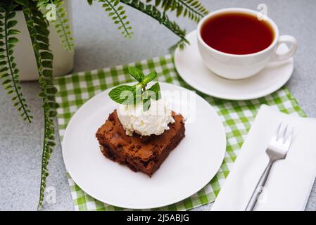 Brownie-Portion mit einer Kugel Vanilleeis darauf. Traditionelles amerikanisches Gebäck. Kakaopulver und Schokolade sind die Hauptzutaten. Stockfoto