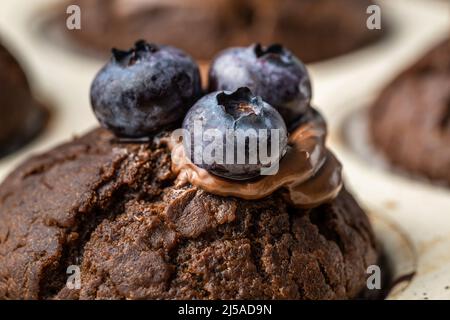 Frisch gebackene Muffins mit Schokoladencreme und Heidelbeeren in einer Keramikpfanne Stockfoto