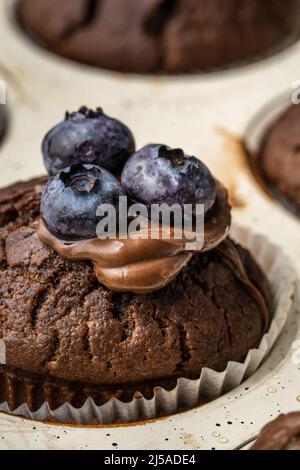 Frisch gebackene Muffins mit Schokoladencreme und Heidelbeeren in einer Keramikpfanne Stockfoto
