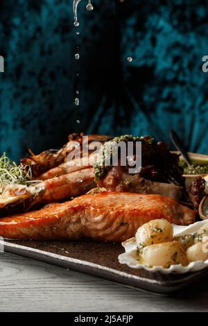 Geröstete gemischte Meeresfrüchte enthalten Muscheln, Garnelen, Lachs, Calamari-Tintenfische und gegrillten Barracuda-Fischklaub mit würziger Chilisauce. Meeresfrüchte und Fleischspieß Stockfoto
