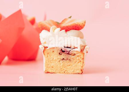 Cupcake in Scheiben mit weißer Creme und Erdbeeren vor rosa Hintergrund Stockfoto