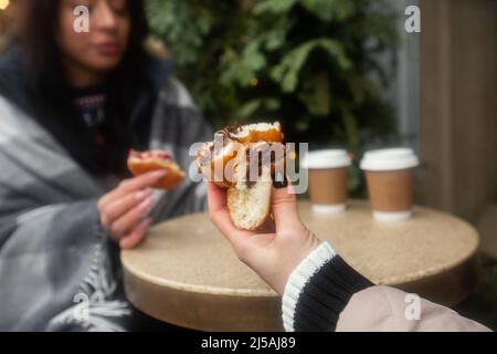 Deutsche Donuts - berliner mit Füll- und Puderzucker in weiblichen Händen. Mädchen genießen Schokolade und Marmelade Füllung Donuts Stockfoto