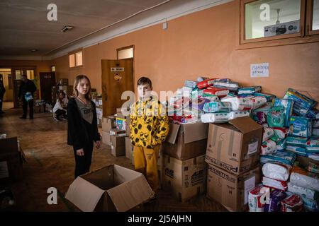 Charkiw, Ukraine. 19. April 2022. Zwei Kinder sahen in einer ehemaligen Schule, die zu einem Depot für humanitäre Hilfe wurde, bei der Verpackung humanitärer Hilfe mithelfen. Während der Krieg an der Ostfront der Ukraine fortschreitet, haben Freiwillige in Charkow ein Versorgungsdepot in einer ehemaligen Grundschule eingerichtet, um verschiedenen Menschen in Not Nahrung, medizinische Versorgung und andere Notwendigkeiten zu liefern. Kredit: SOPA Images Limited/Alamy Live Nachrichten Stockfoto