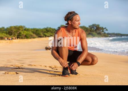 Smartwatch Fitness-Läufer bindet Schuhe, um beim Sommertraining am Strand zu laufen. Gesunder, aktiver Lebensstil, Lauftraining Stockfoto