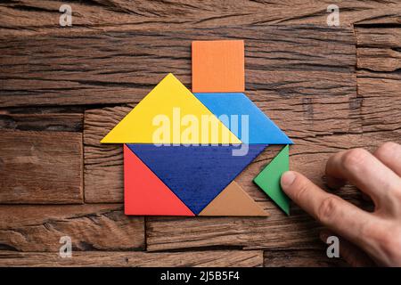 Miniaturhaus Puzzle Stücke Und Tangram. Holzspielzeug Immobilien Stockfoto