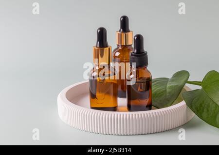 Set von nicht gebrandeten dunklen Glasflaschen für Design. Ätherisches Öl, Gesichtsserum und Essenz in Mock-up-Paket. Minimalistischer Style. Trendiges Konzept Stockfoto