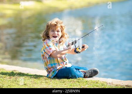 Lustige glückliche kleine Kind Angeln am Wochenende. Ein Fischerjunge steht mit einer Angelrute im See und fängt Fische. Stockfoto