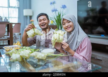 muslim paar asiatische Herstellung Ketupat Reiskuchen zu Hause mit Palmblatt Stockfoto