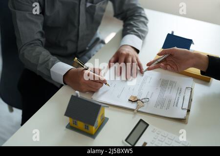 Immobilienmakler stimmen zu, ein Haus zu kaufen und geben den Kunden Schlüssel in den Büros ihrer Agentur. Konzeptvereinbarung Stockfoto