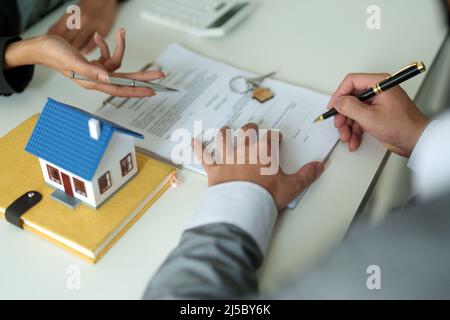 Immobilienmakler stimmen zu, ein Haus zu kaufen und geben den Kunden Schlüssel in den Büros ihrer Agentur. Konzeptvereinbarung Stockfoto