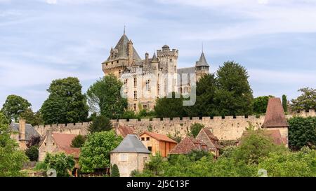 Chateau de Montfort auf einem Hügel und einem Dorf, das sich unter einem bedeutenden Burgwall mit attraktiven Häusern in der Region Dordogne, Frankreich, befindet Stockfoto