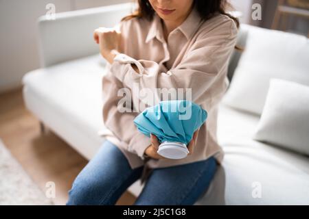 Frau, Die Eisgelpackung Am Verletzten Arm Verwendet Stockfoto