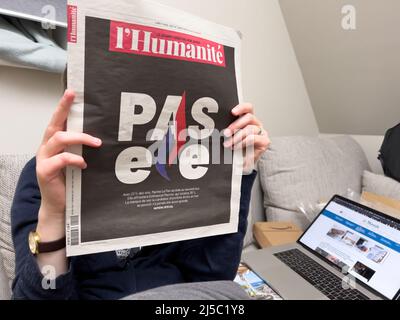 Paris, Frankreich - 21. Apr 2022: Frau liest auf der Couch l'Humanite Zeitung Emmanuel Macron, Marine Le Pen einen Tag nach der ersten Runde der französischen Präsidentschaftswahlen am 10 2022. April Stockfoto
