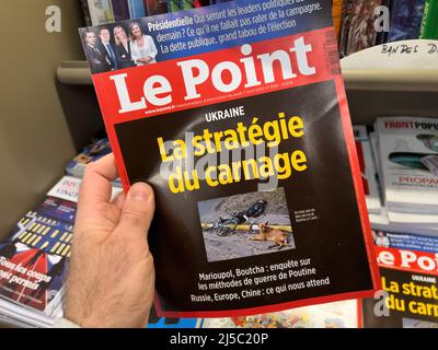 Paris, Frankreich - 11. Apr 2022: Mann kauft am Zeitungskioster das internationale Zeitungsmagazin Le Point mit toten Menschen auf den Straßen der Ukraine - russische Invasion in der Ukraine Schlagzeile Stockfoto